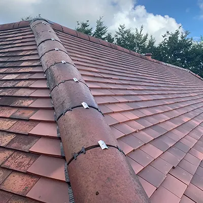 A close up of a red roof with a blue sky in the background.
