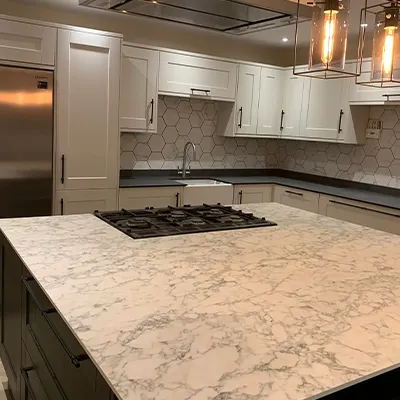 A kitchen with marble counter tops and white cabinets.